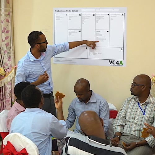 Man in blue shirt giving VC4A presentation to engaged audience